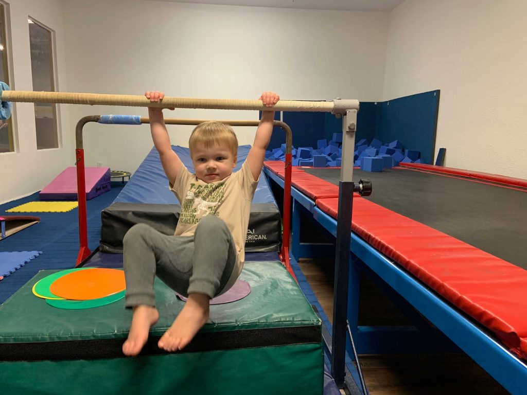 preschool boy swinging on gymnastics bar